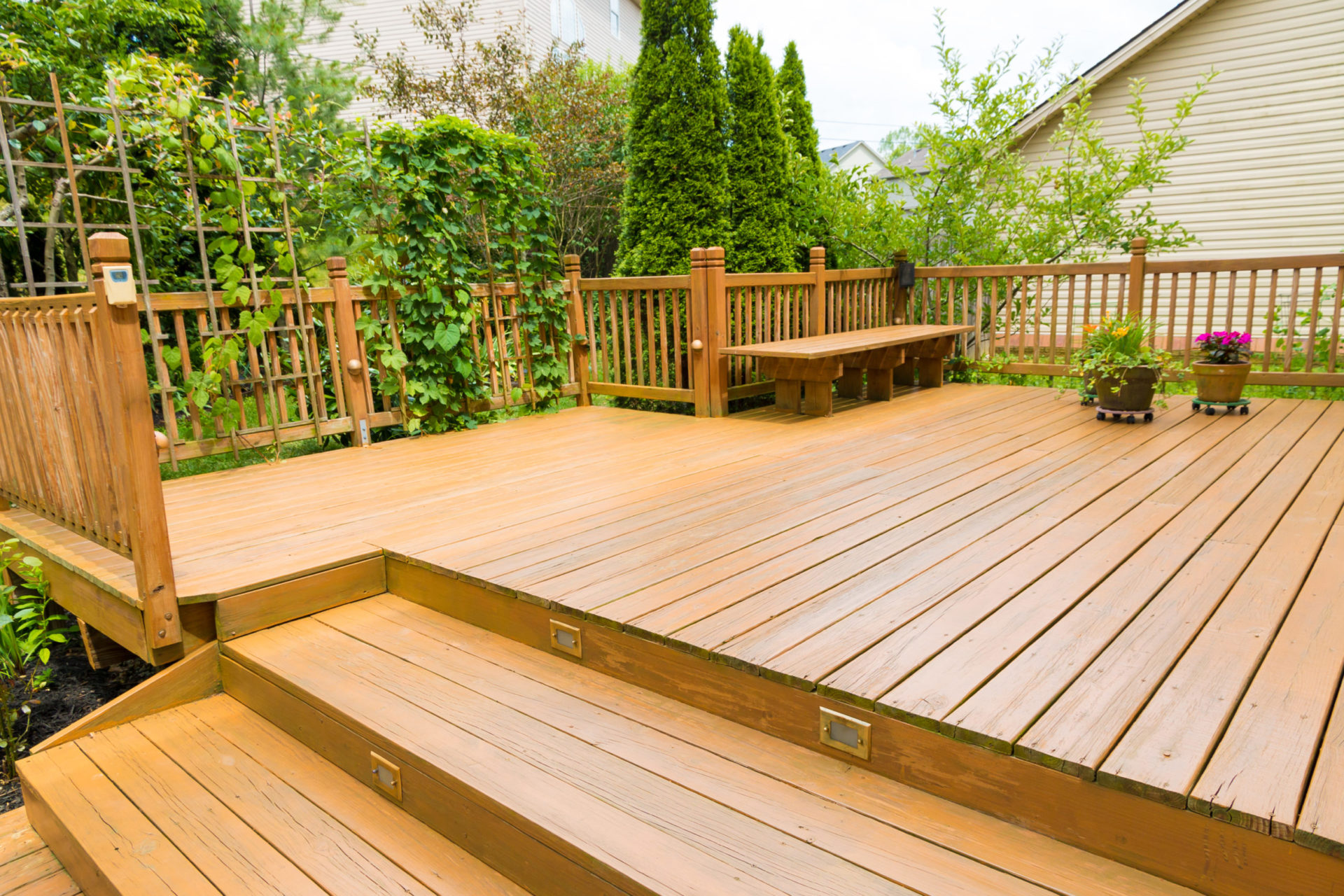 A wooden deck with stairs and fencing in a backyard