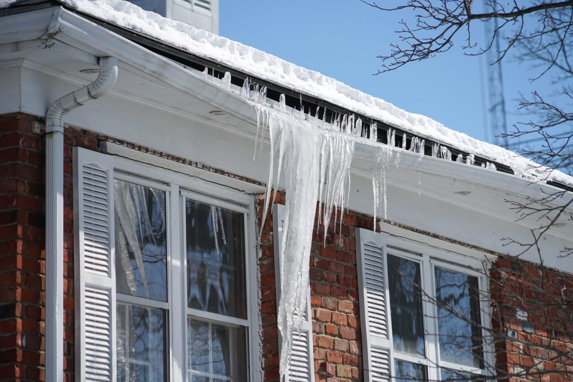 icicles on house roof, clear blue sky