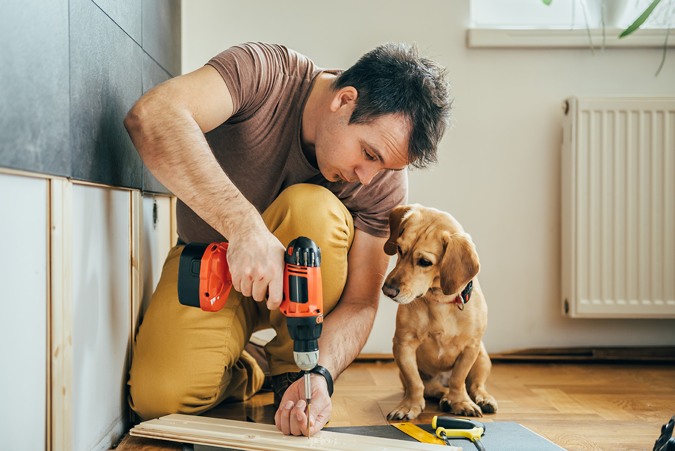 Man working on flooring with a puppy