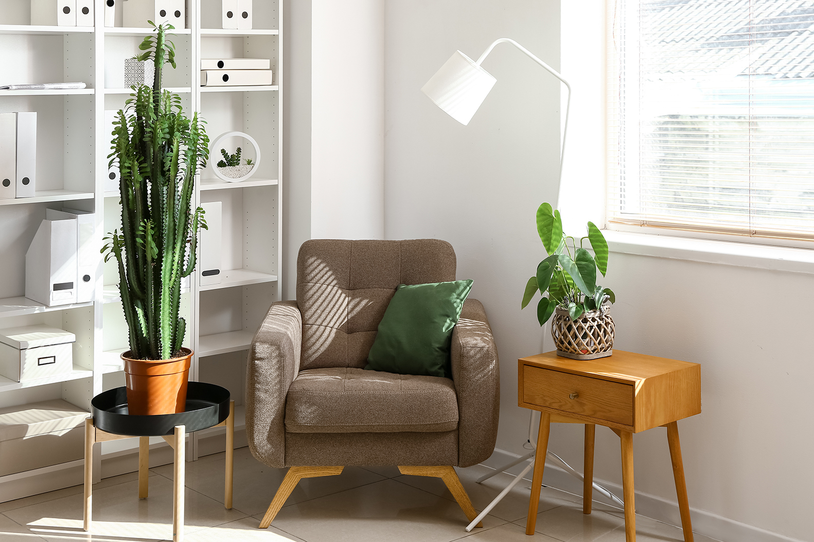 A comfortable chair with pillows and plants on side tables