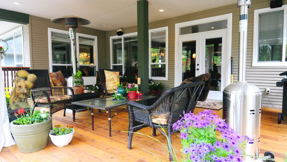 Outdoor patio with table and chairs. Colorful flowers and heater.