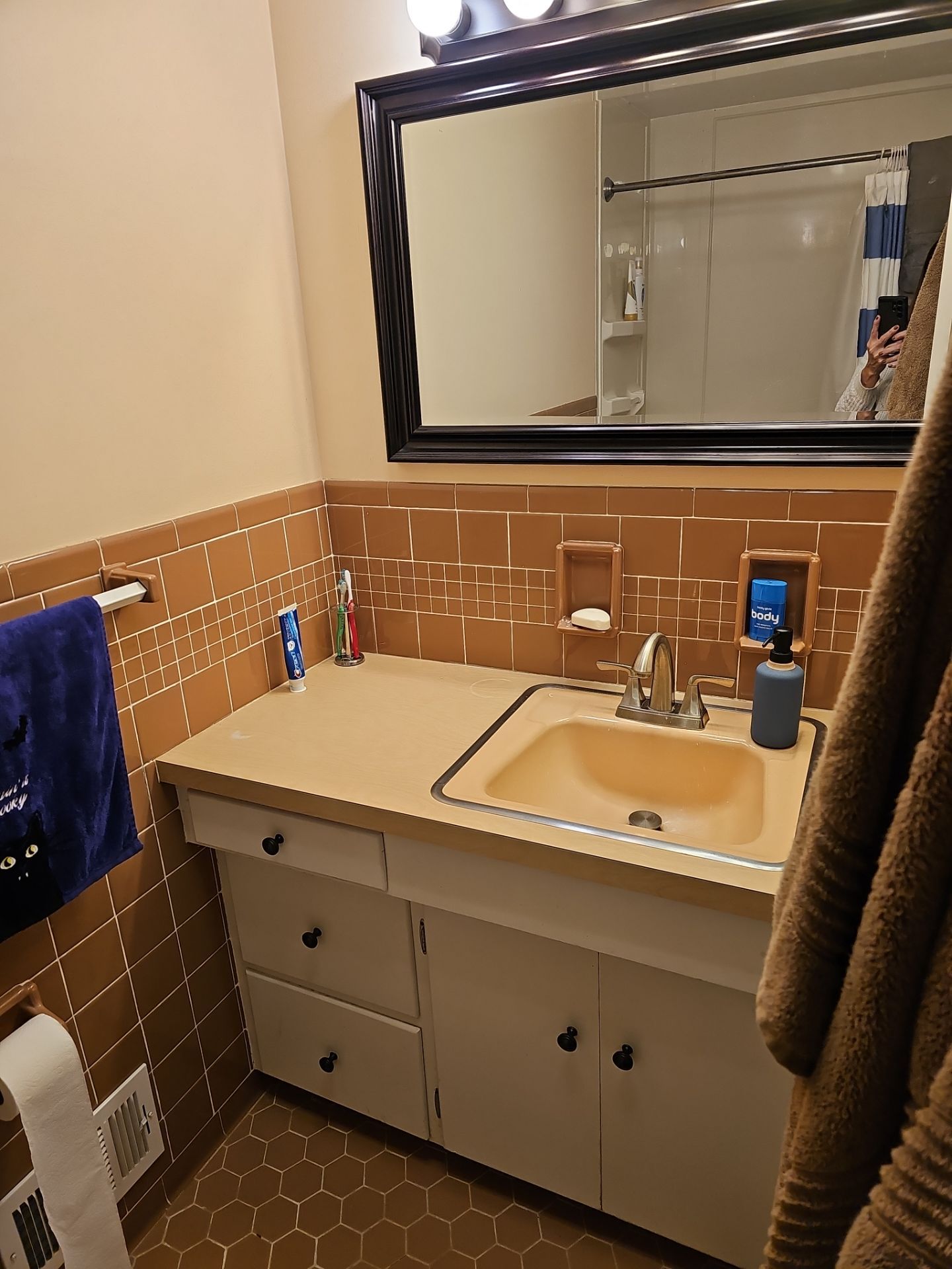 Bathroom with orange tile and white sink. Towel hanging on rack.