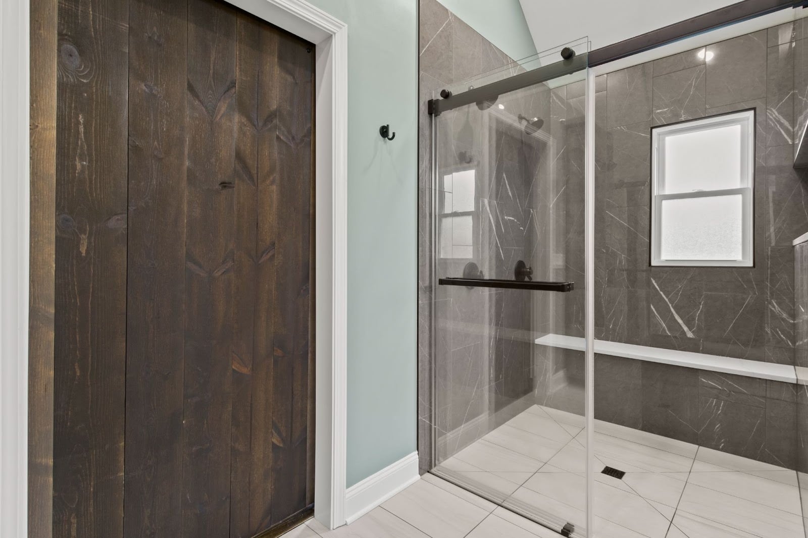 Modern bathroom interior with a wooden door and a glass-enclosed shower area.