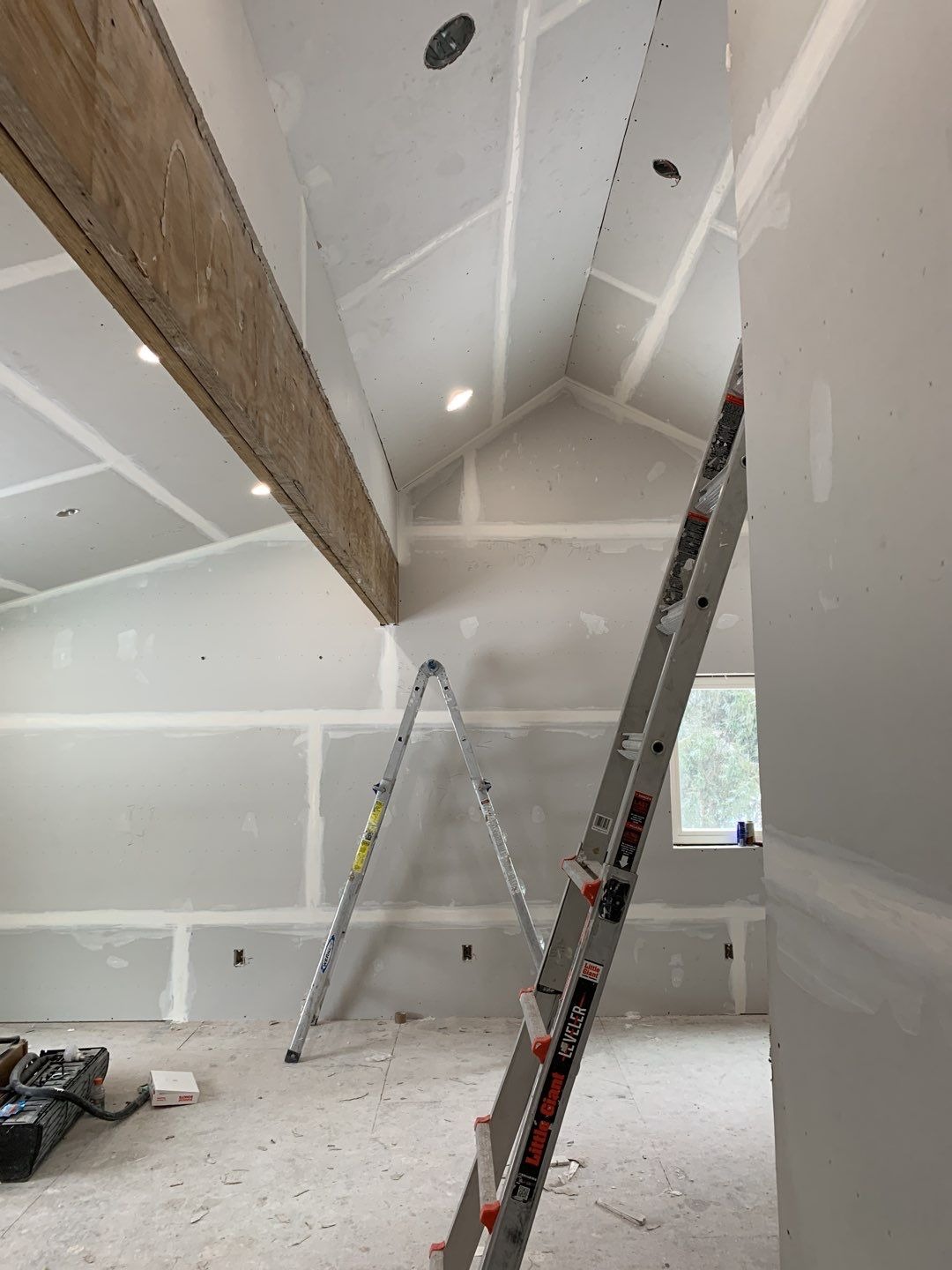 A construction site with a ladder and unfinished drywall. The room is under renovation.