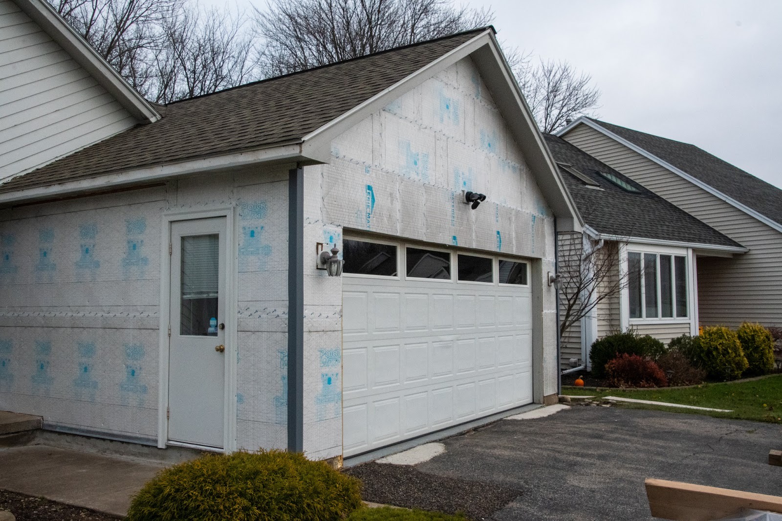 A house with a garage under renovation. The garage door is white.