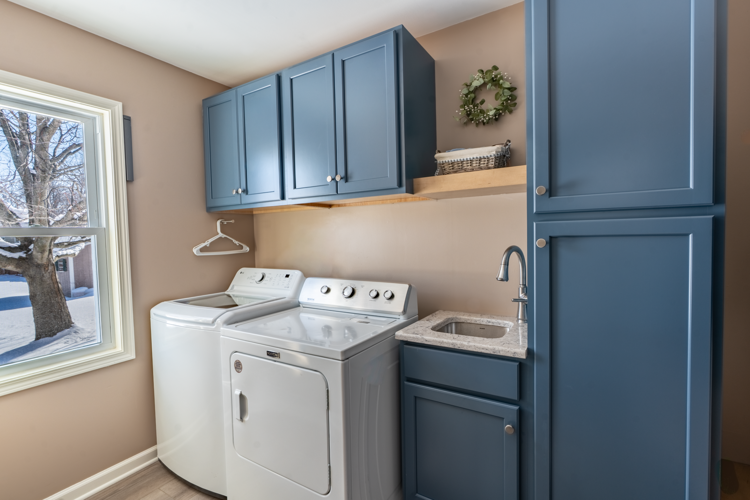 A laundry room with blue cabinets and white washer and dryer