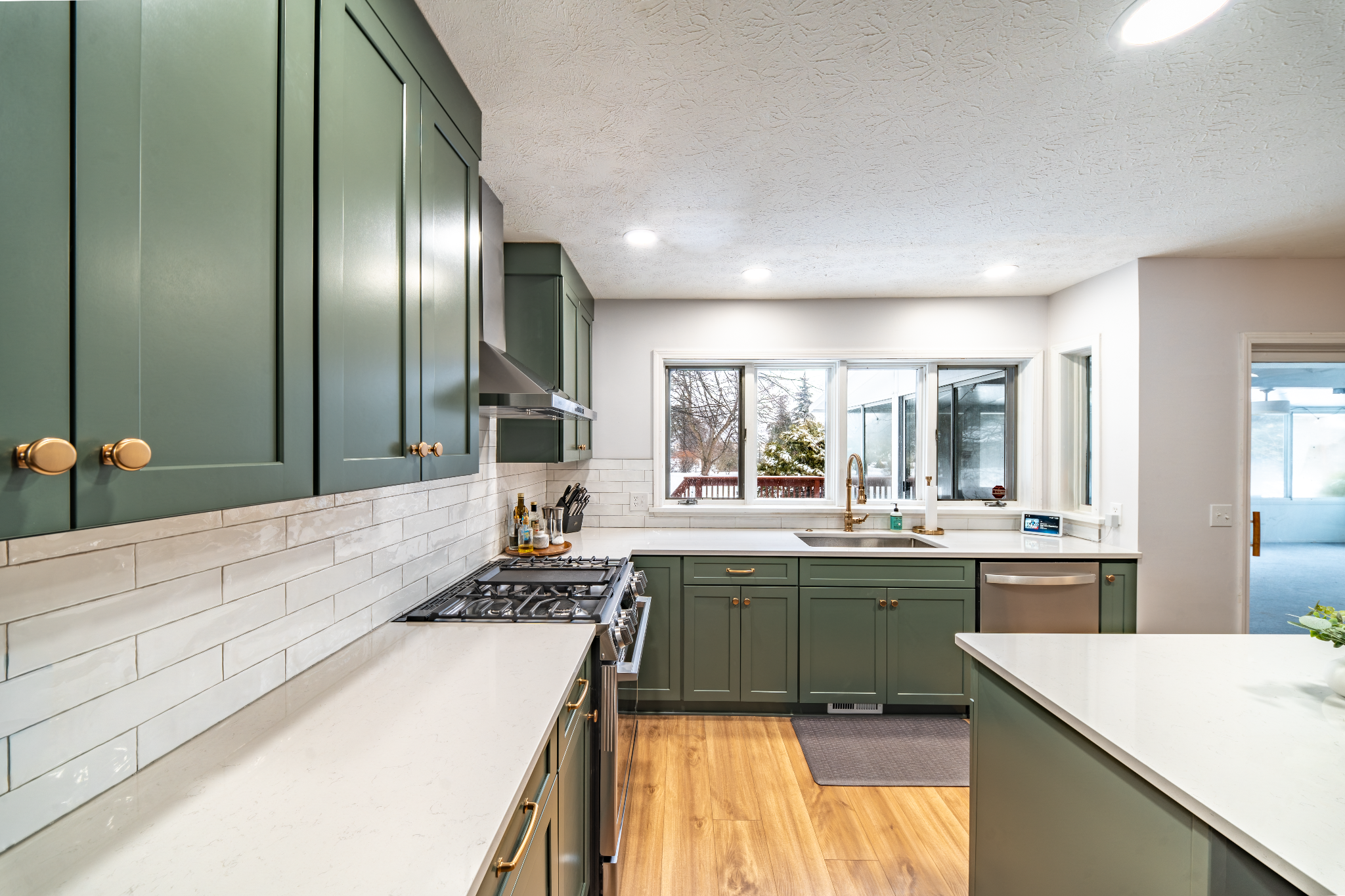 Modern kitchen interior with green cabinets and white counters. Kitchen island and sink area