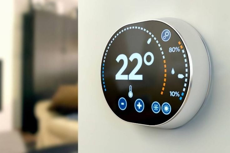 A smart thermostat mounted on a wall, displaying 22 degrees.