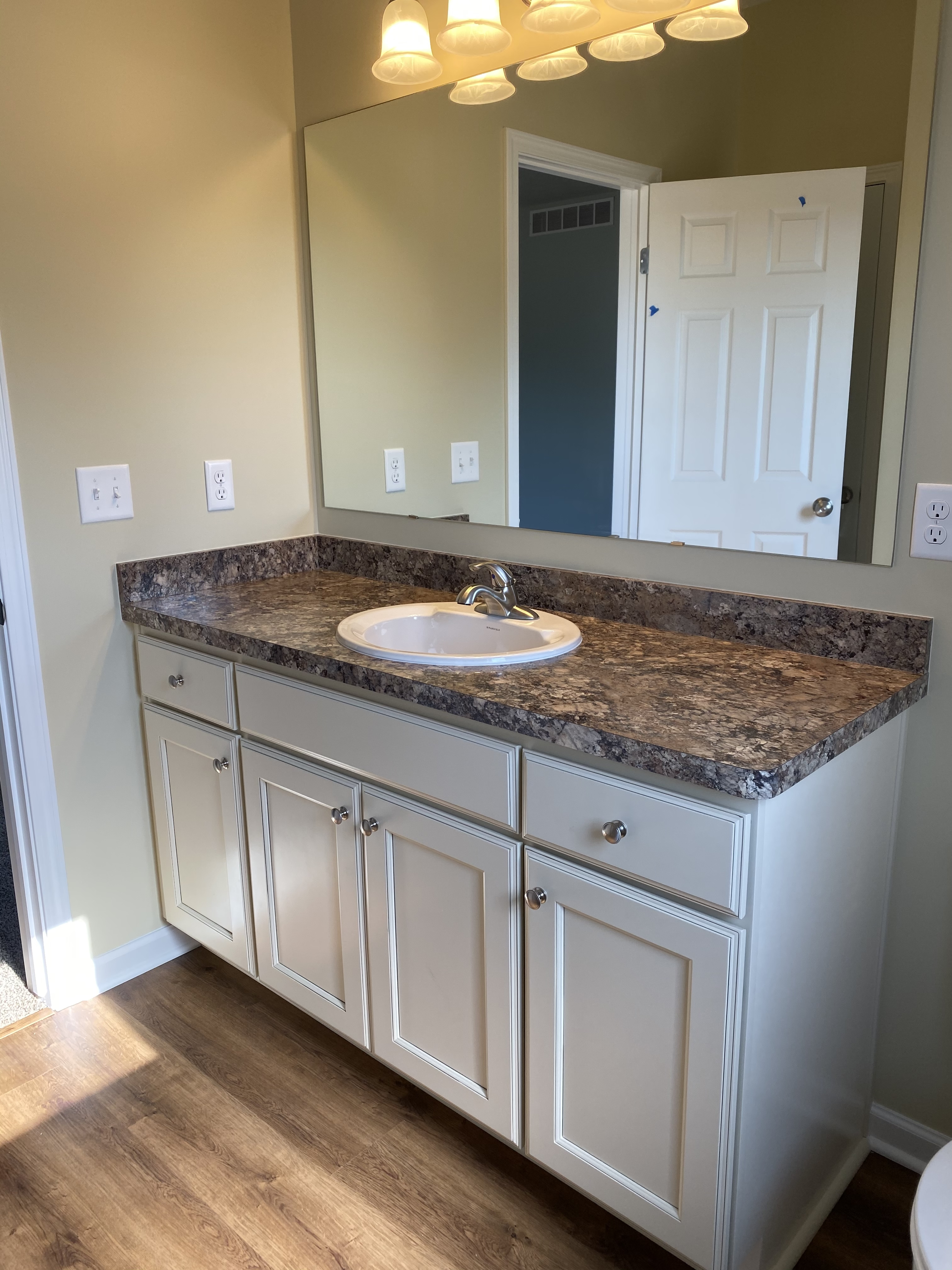 Bathroom vanity with marble countertop and sink. White cabinets and large mirror.