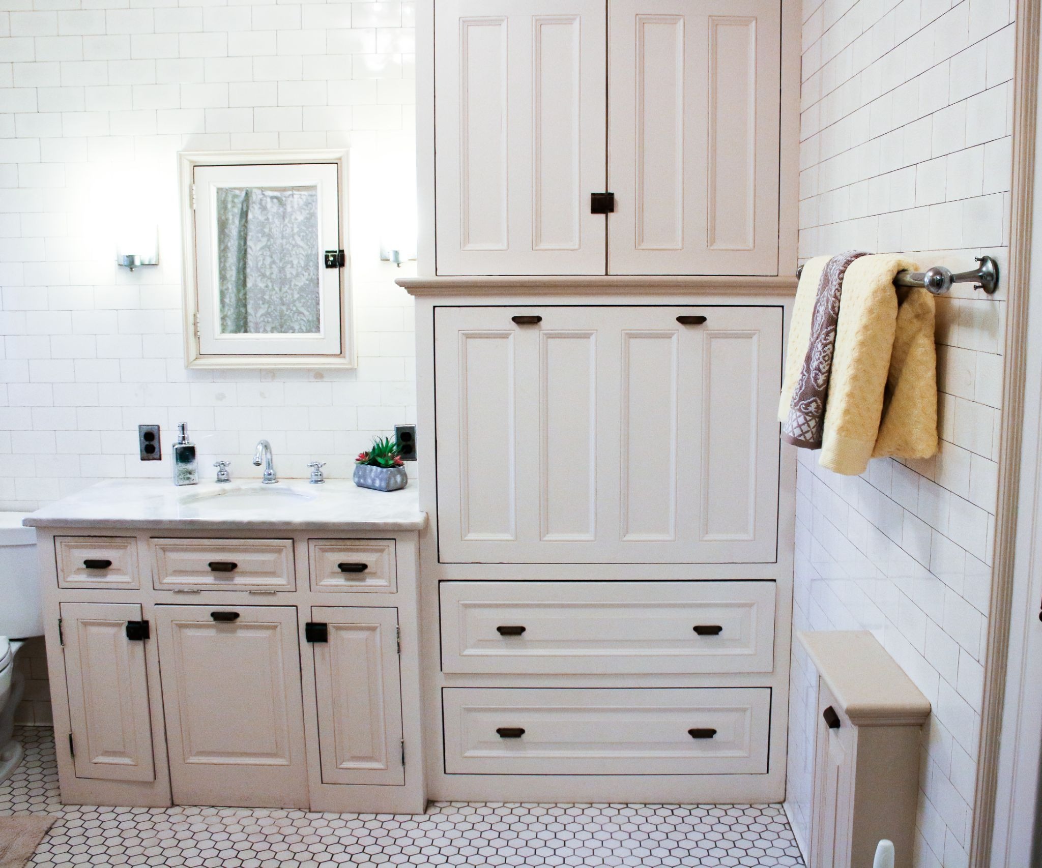 Bathroom interior with beige cabinets and white countertop. Modern bathroom design with towels hanging on the wall.