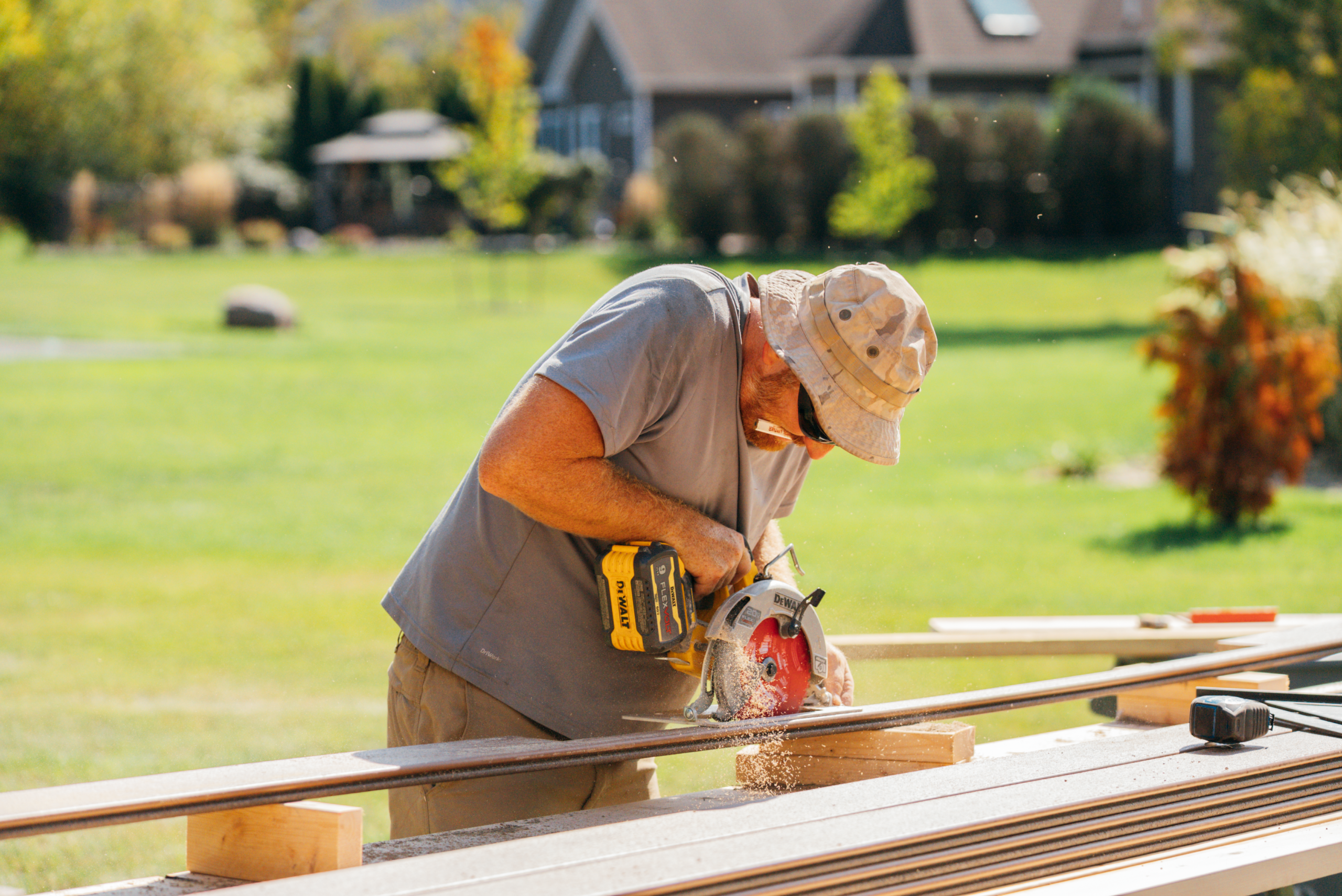 Man in a hat using a power saw on lumber