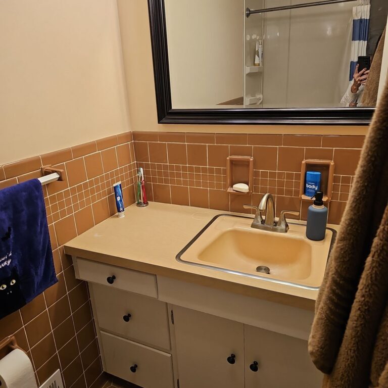 Bathroom with orange tile and white sink. Towel hanging on rack.
