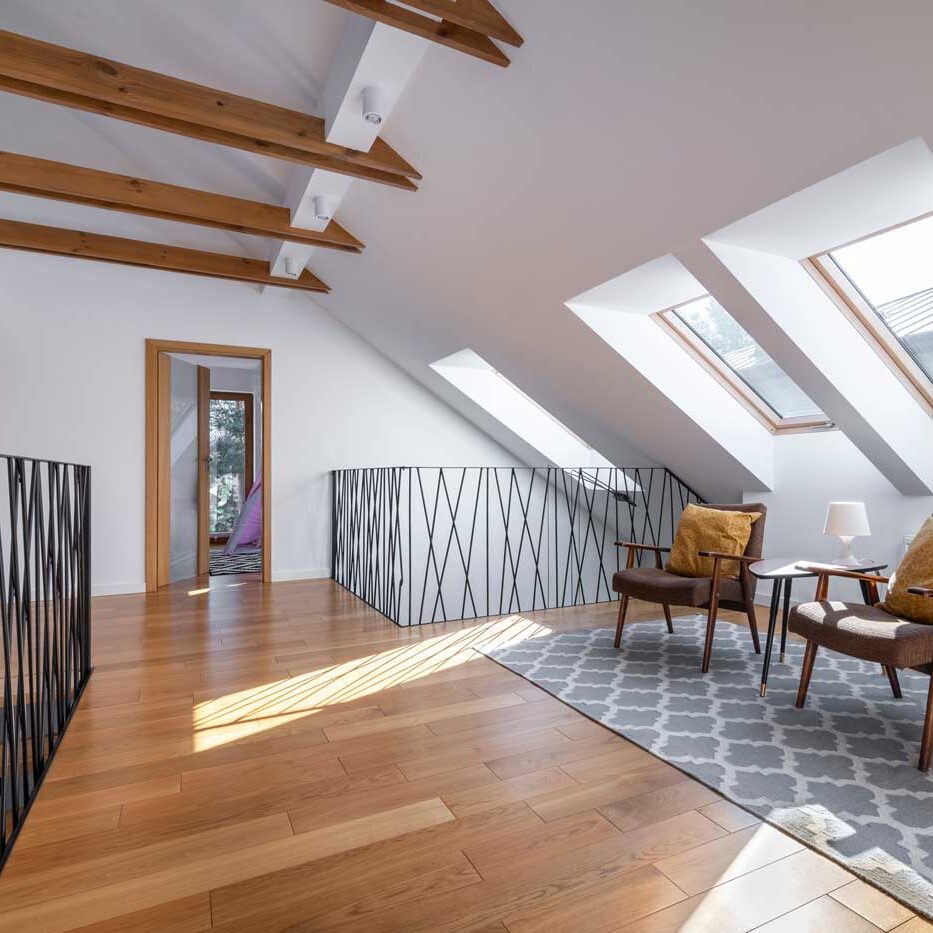 Attic room with wooden floor and chairs. Natural light pouring in.