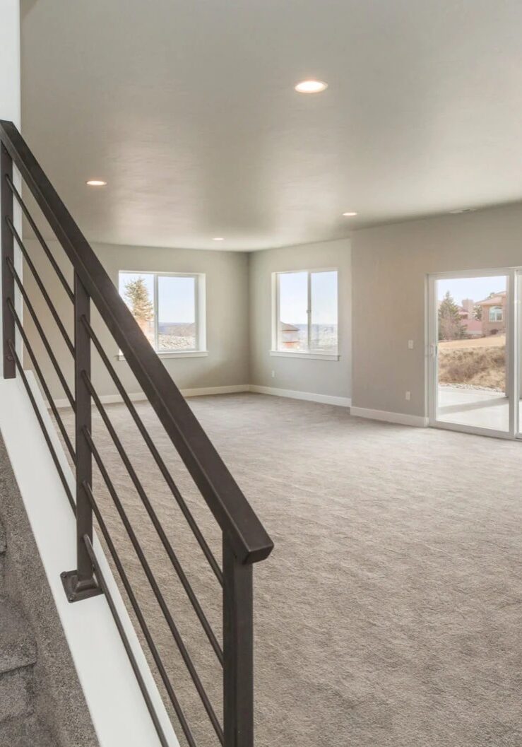 A modern home interior featuring a staircase and elevator. The room is empty with large windows.