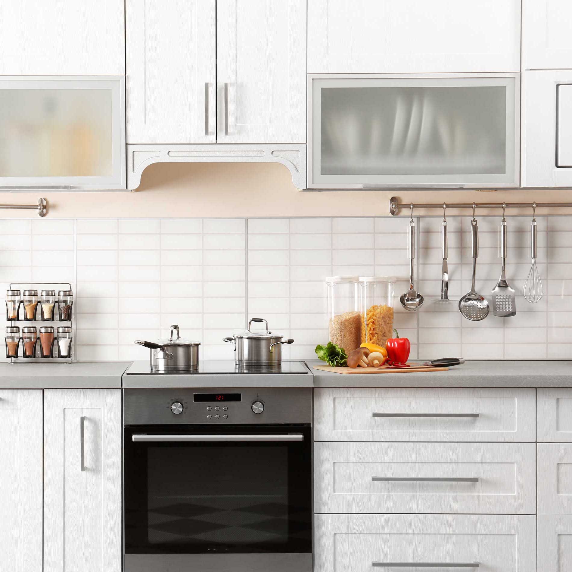 A modern kitchen with white cabinets, stainless steel appliances, and a countertop with a blender and fruit.