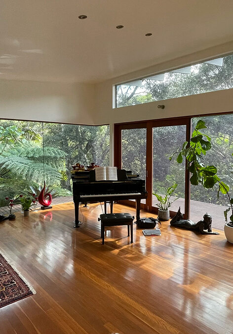 A music room with a piano, plants, and a fireplace